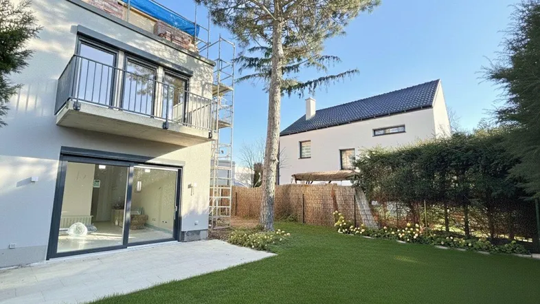 Moderne Hausfassade mit großzügiger Rasenfläche und Terrasse im Bauzustand.