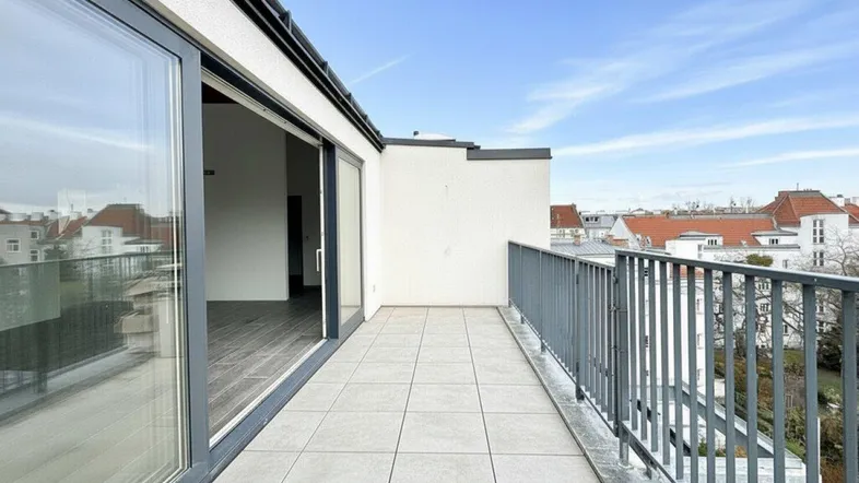 Geräumiger Balkon mit Fliesenboden und weitem Blick über die Dächer der Stadt.