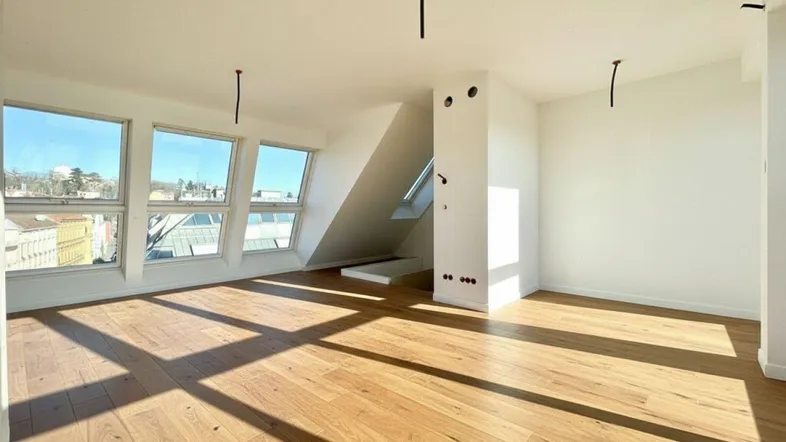 Geräumiges, helles Zimmer mit Holzboden und Dachfenstern, die den Raum mit Licht füllen.