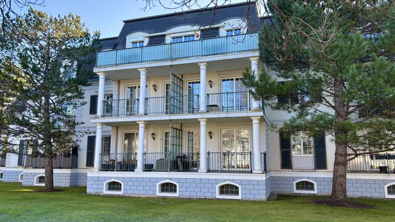 Elegante Fassade eines Mehrfamilienhauses mit mehreren Balkonen und gepflegtem Vorgarten.