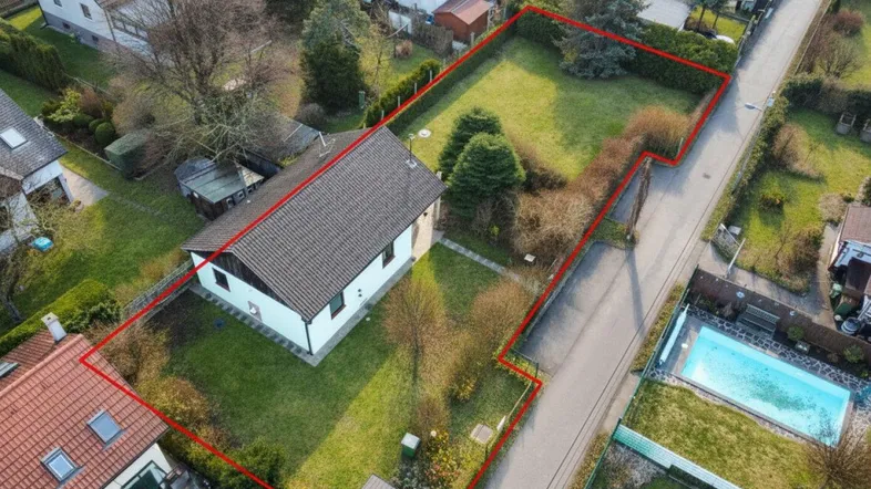 Luftaufnahme eines Einfamilienhauses mit großem Garten und roter Grundstücksumrandung in ländlicher Umgebung.