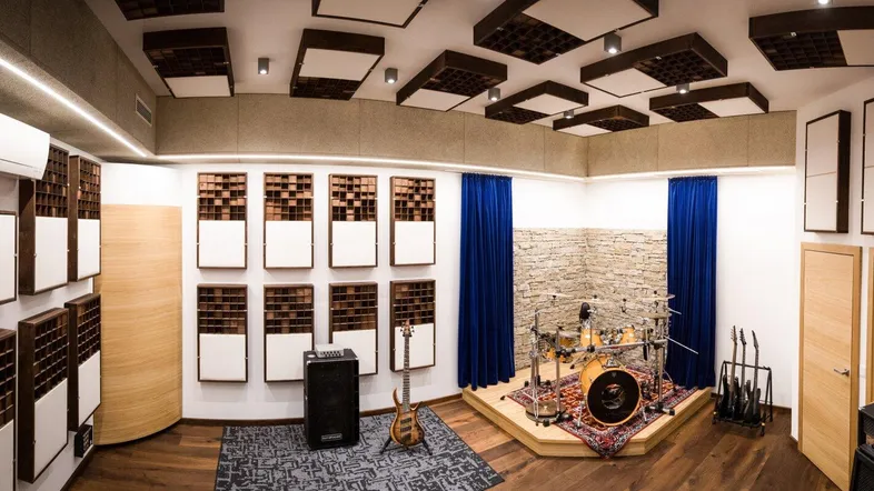 Professionelles Musikstudio mit Akustikpaneelen, Schlagzeug und Mischpult für optimale Klangqualität.