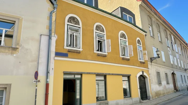 Historisches Gebäude mit gelber Fassade, verzierten Fenstern und Dachgauben.