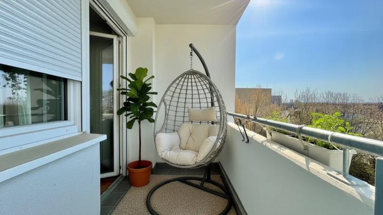 Sonniger Balkon mit bequemer Hängesessel und Pflanzen, ideal zum Entspannen im Freien.