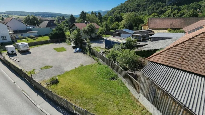Luftaufnahme eines unbebauten Grundstücks mit Rasenfläche und Blick auf die umliegende Hügellandschaft.