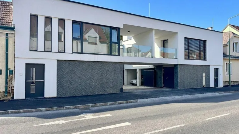 Moderne Wohnanlage mit weißer Fassade, großen Fenstern und integrierten Garagen.
