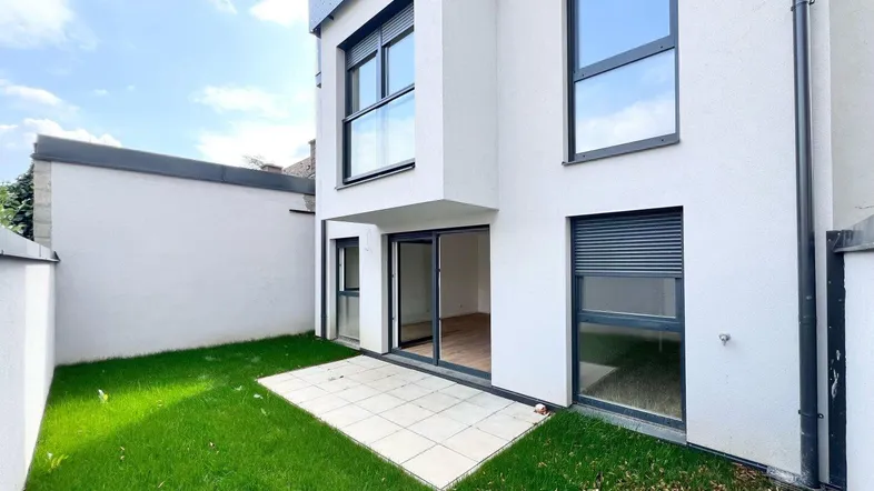 Moderne Hausfassade mit privatem Gartenbereich und kleiner Terrasse.