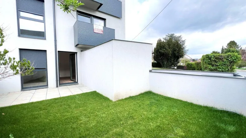 Moderne Wohnanlage mit privatem Gartenbereich und Terrasse im Erdgeschoss, umgeben von Grün.