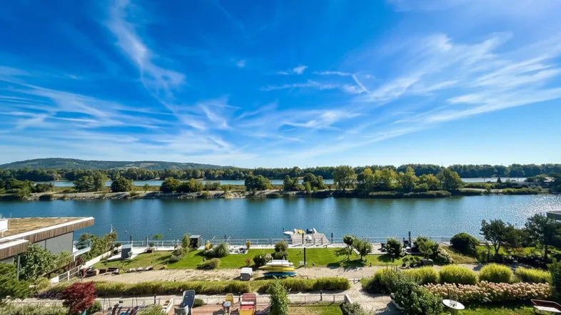 Panoramablick auf den Fluss und die grüne Landschaft mit einem gepflegten Gartenbereich im Vordergrund.