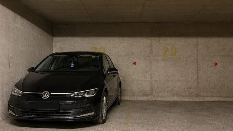 Tiefgaragenstellplatz mit Betonwänden und -decke, inklusive einem geparkten Fahrzeug.