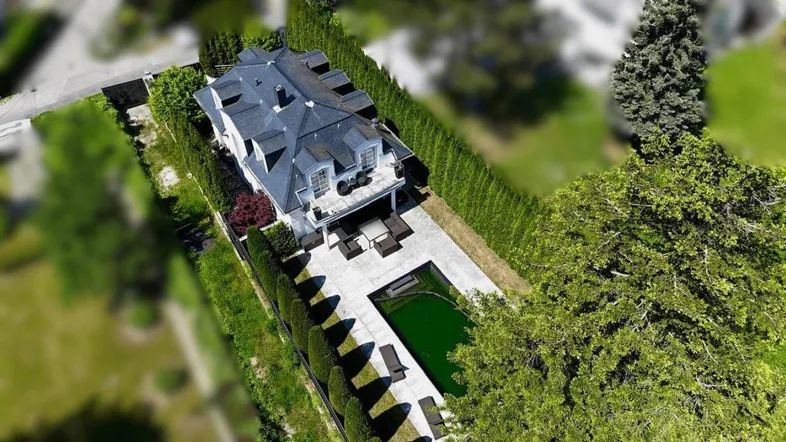 Luftaufnahme des Anwesens mit Pool, Garten und dem eleganten Mansarddach des Hauses.