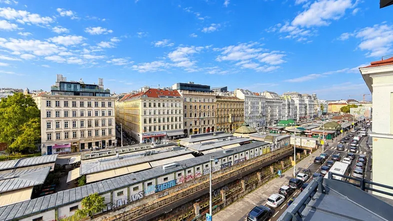 Weitläufiger Blick über die Stadt mit historischen Gebäuden, Marktständen und belebter Straße.