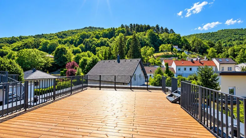 Weitläufige Dachterrasse mit Holzboden und Panoramablick auf die bewaldeten Hügel.