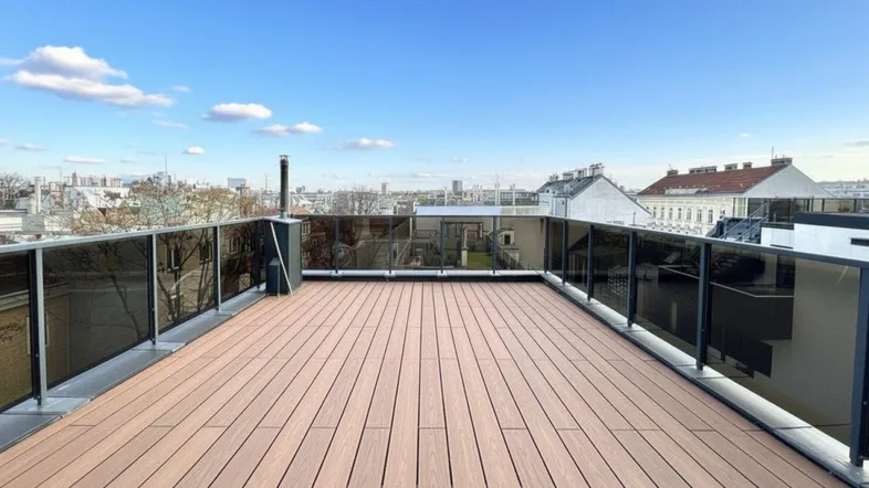 Große Dachterrasse mit Holzdielenboden und Glasgeländer bietet einen weiten Blick über die Stadt.