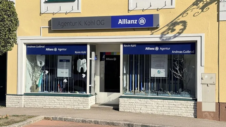Gebäudefassade mit Schaufenstern einer Allianz-Agentur, die sich im Erdgeschoss befindet.