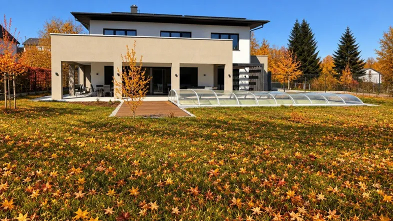 Modernes Haus mit großem Garten, überdachtem Pool und Terrasse an einem sonnigen Herbsttag.