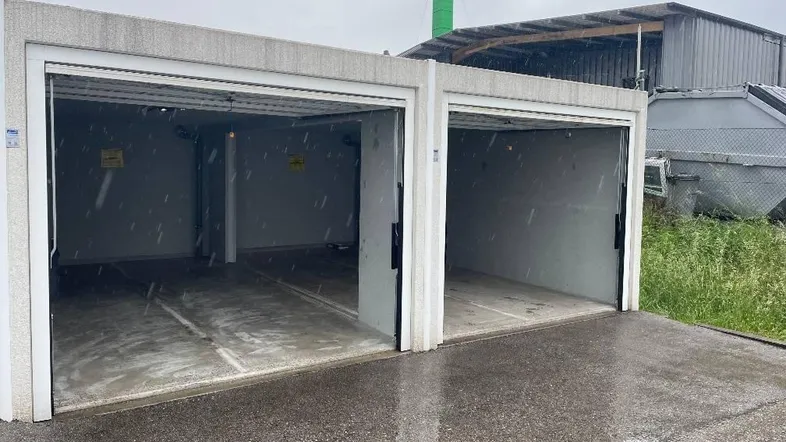 Zwei separate Garagen mit geöffneten Toren und Betonkonstruktion im Freien.