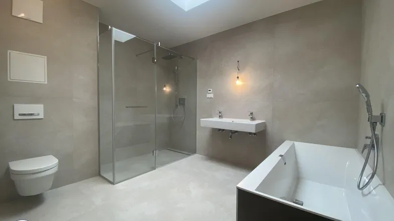 Modernes Badezimmer mit großer begehbarer Dusche, Badewanne, Doppelwaschbecken und Dachfenster für viel Tageslicht.