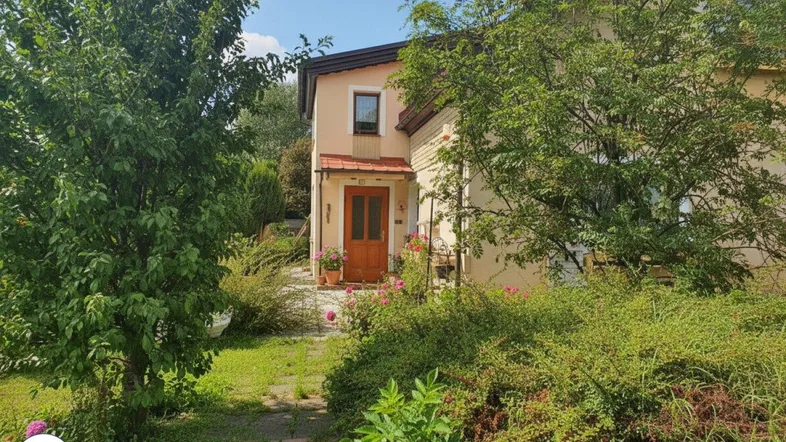 Vorderansicht des Hauses mit gepflegtem Vorgarten, Bäumen und einem Steinweg zum Eingang.