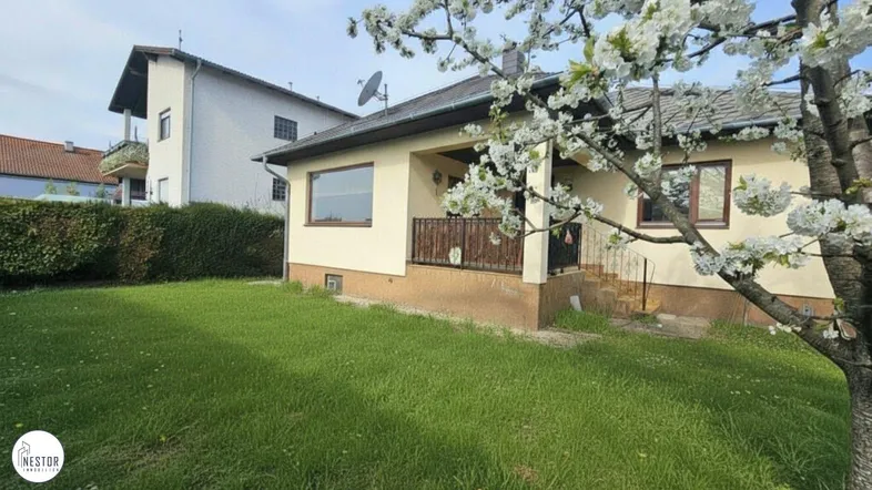 Einfamilienhaus mit gepflegtem Garten und blühendem Baum im Frühling.