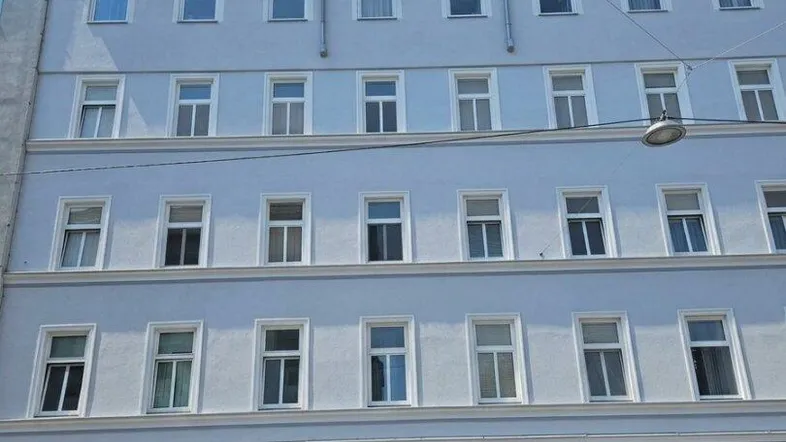 Die Fassade des Mehrfamilienhauses präsentiert sich in hellem Grau mit zahlreichen Fenstern und Dachgauben.