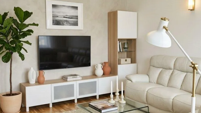 Helles Wohnzimmer mit beigem Sofa, modernem TV-Möbel und Holzboden für entspannte Abende.