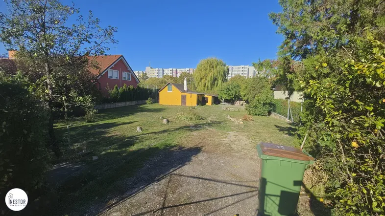 Großer Gartenbereich mit Rasenfläche, Bäumen und Blick auf umliegende Gebäude.