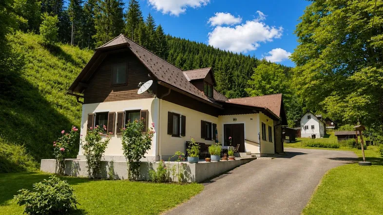 Traditionelles Haus in ländlicher Umgebung mit grünen Hügeln und Wald im Hintergrund.