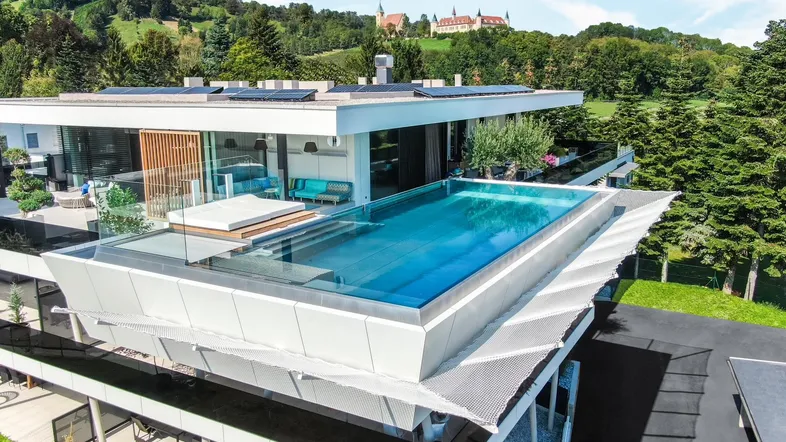 Luxuriöses modernes Gebäude mit einem beeindruckenden Infinity-Pool auf dem Dach und Panoramablick auf die Landschaft.