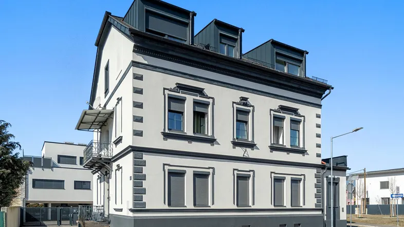 Historisches Gebäude mit modernisierten Dachgauben, klassischer Fassadengestaltung und kleinem Balkon.