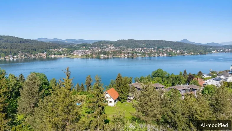 Panoramablick auf den Wörthersee mit umliegender Landschaft und Häusern am Ufer.