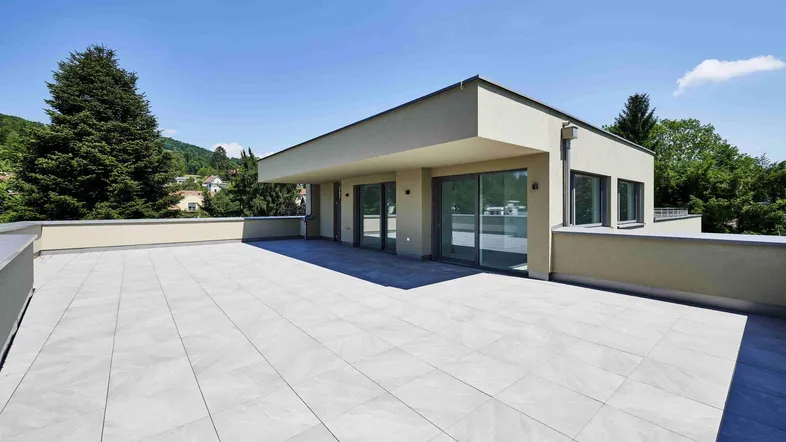 Geräumige Dachterrasse mit hellen Fliesen und weitem Blick in die grüne Umgebung.