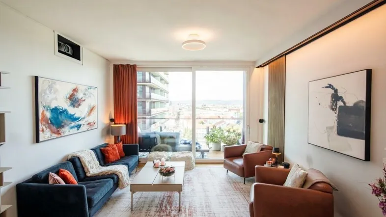 Helles Wohnzimmer mit bequemen Sofas, modernen Kunstwerken und Zugang zum Balkon.