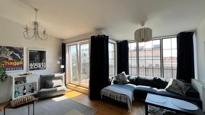 Helles Wohnzimmer mit großem Sofa, Holzboden und Zugang zur Terrasse.