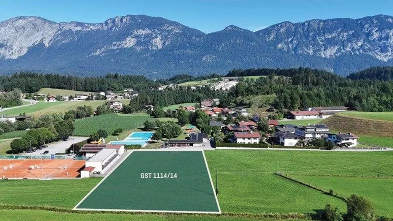 Luftaufnahme einer ländlichen Gegend mit Bergen, Feldern, einem Dorf und einem markierten Grundstück.
