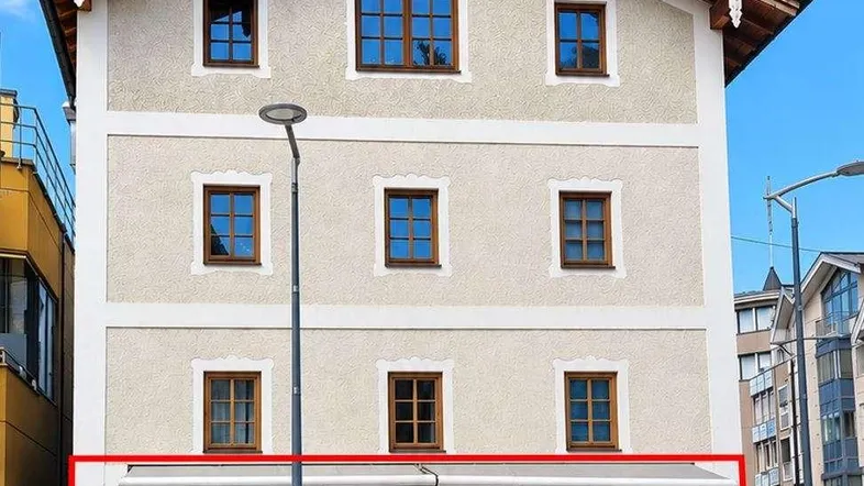 Vorderansicht eines mehrstöckigen Gebäudes mit einem Einzelhandelsgeschäft im Erdgeschoss und Wohnungen darüber.