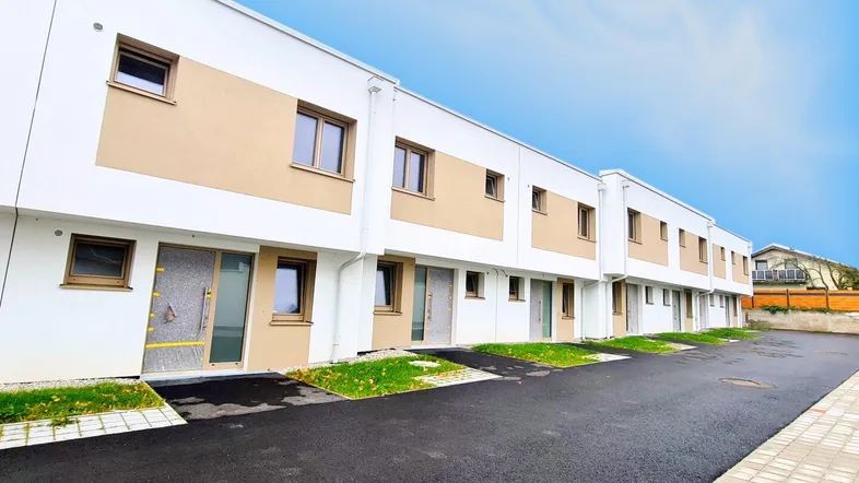 Reihenhäuser in moderner Architektur mit weißer Fassade und beigen Akzenten unter blauem Himmel.