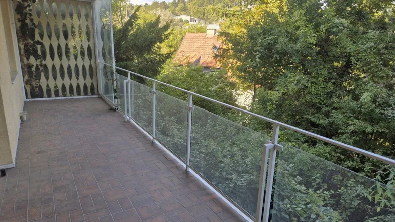 Geräumiger Balkon mit Glasgeländer und Blick ins Grüne, ideal für entspannte Stunden im Freien.