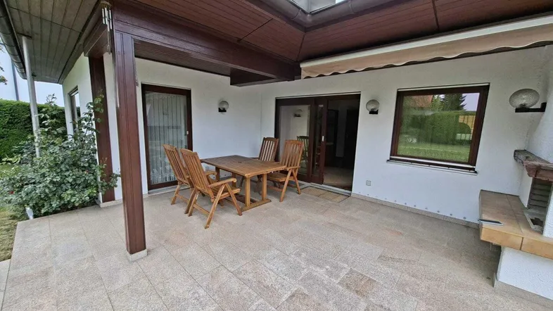 Geräumige Terrasse mit Holztisch und Stühlen, ideal für Mahlzeiten im Freien und Entspannung.