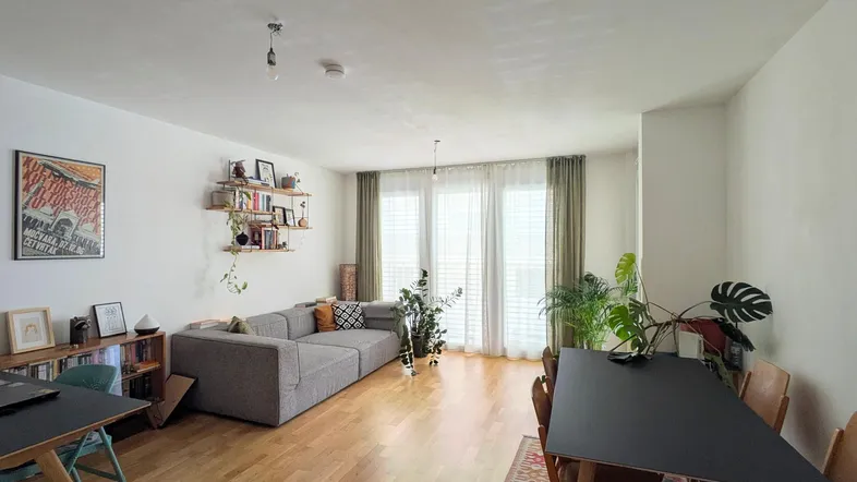 Heller, offener Wohn- und Essbereich mit Parkettboden, großem Sofa und Esstisch.
