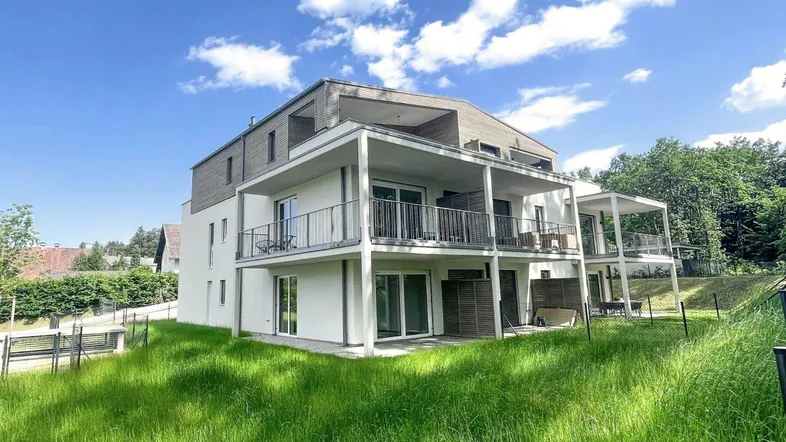 Modernes Mehrfamilienhaus mit Balkonen, Terrassen und viel Grünfläche in sonniger Lage.