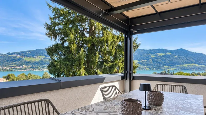 Geräumige Terrasse mit modernen Gartenmöbeln und atemberaubendem Blick auf den See und die Berge.