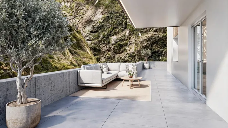 Moderne Terrasse mit bequemen Outdoor-Möbeln, Fliesenboden und Blick auf die grüne Berglandschaft.