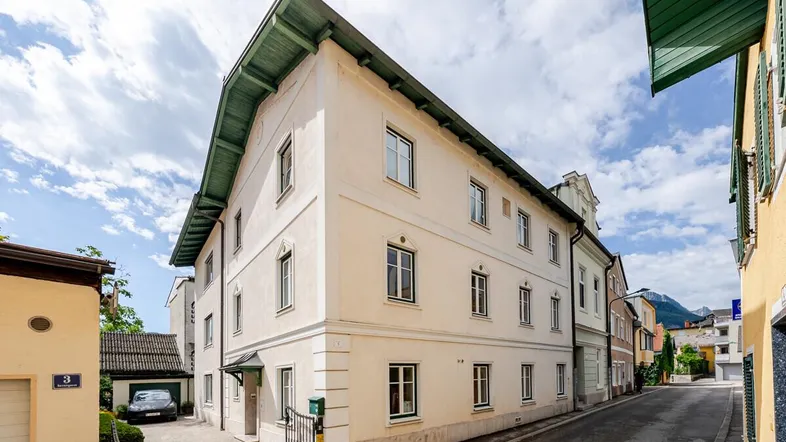 Historisches Gebäude mit heller Fassade und traditionellem Dach in einer ruhigen Gasse.