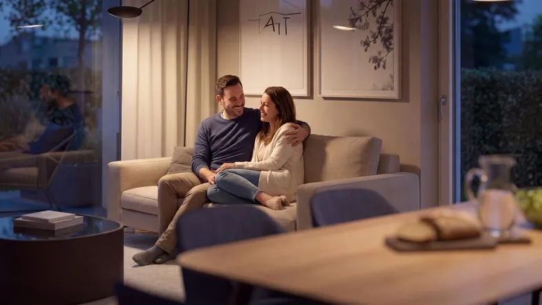 Gemütliches Wohnzimmer mit einem Paar auf dem Sofa und Blick auf den Garten.