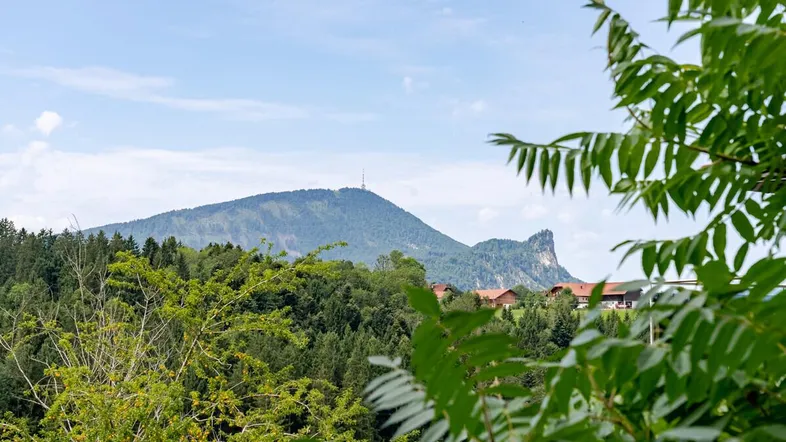 Panoramablick auf die majestätischen Berge und die umliegende grüne Landschaft mit vereinzelten Häusern.