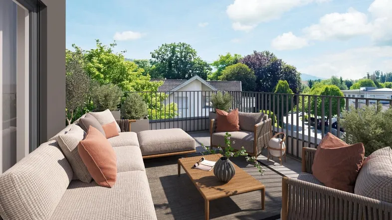 Geräumige Terrasse mit modernen Outdoor-Möbeln und Blick ins Grüne unter blauem Himmel.