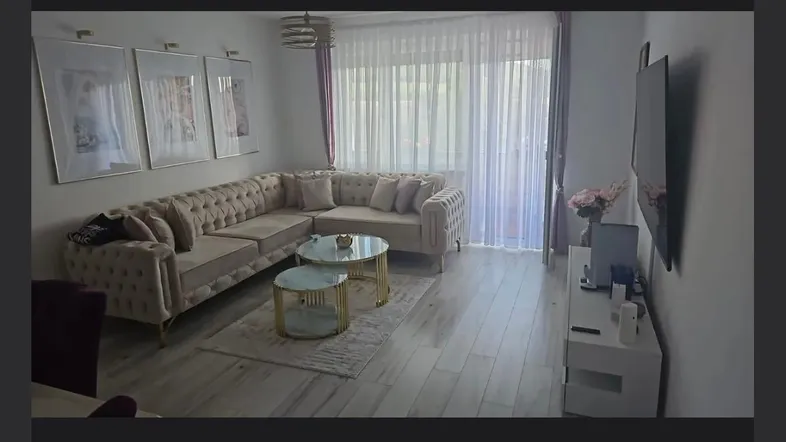 Helles Wohnzimmer mit großem Ecksofa, modernen Couchtischen und viel Tageslicht durch die Fenster.