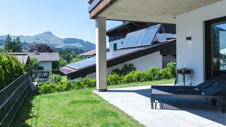 Sonniger Außenbereich mit Liegestühlen, gepflasterter Terrasse und herrlichem Bergblick.