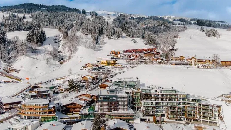 Panoramablick auf das verschneite Bergdorf mit modernen Gebäuden und Skipisten.